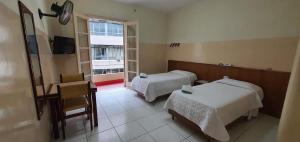 a room with two beds and a desk and a window at Hotel Plaza Olido in São Paulo