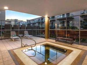 a patio with a pool on a building with two chairs at Mantra The Observatory in Port Macquarie