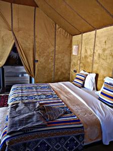 a bed in a tent with pillows on it at Zahra Luxury Desert Camp in Merzouga
