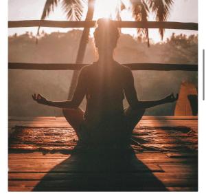 a woman sitting in a yoga pose in the sunset at Bhuvanavasigal alayam in Tiruvannāmalai