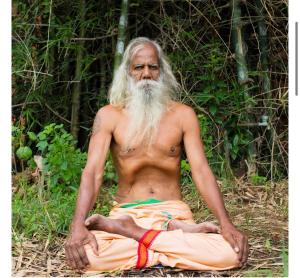 a man with a long beard sitting on the ground at Bhuvanavasigal alayam in Tiruvannāmalai