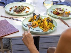 a person sitting at a table with plates of food at Peppers Beach Club & Spa in Palm Cove