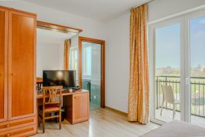 a bedroom with a desk with a television and a balcony at Hotel Nuova Barcaccia in Peschiera del Garda