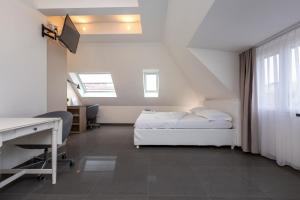 a bedroom with a bed and a desk and window at Hotel Kernhof Self Check-In in Zurich