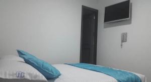 a bedroom with a bed with blue pillows and a television at Hotel Exito La 21 in Pereira