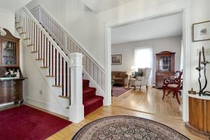 a living room with a staircase with a red rug at The Nicholson Inn in Freeport