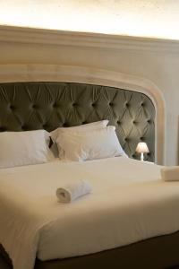 a white bed with a large headboard with a towel on it at Palazzo Del Duca Hotel & Restaurant in Matera