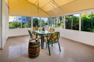 a dining room with a table and chairs and windows at Flora Beach House in Kremasti