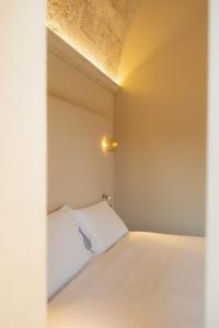 a bedroom with a white bed with a light on it at Palazzo Del Duca Hotel & Restaurant in Matera