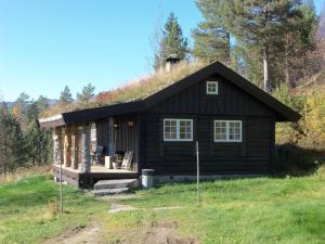 una pequeña cabaña de madera con una colina detrás de ella en Hogstul Hytter - Skojestua - 2 Bedroom Cottage, en Tuddal