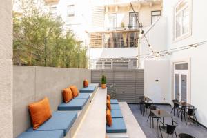 an outdoor seating area with blue benches and orange pillows at Inspira Santos Boutique Hotel in Lisbon
