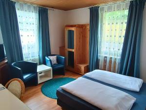 a bedroom with a bed and a chair and windows at Hotel Pfaff in Triberg