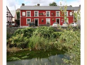 a red building with a river in front of it at Y Llew Coch Tregaron in Tregaron