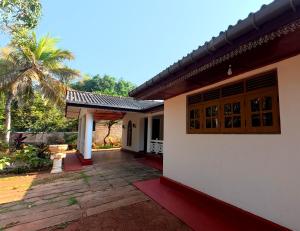 a white house with a palm tree in front of it at Diws Holiday Bungalow in Anuradhapura