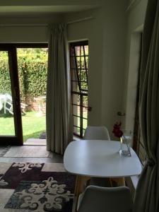 a white table and chairs in a room with a door at Plovers Rest in George