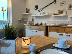 a kitchen with a wooden table and a kitchen counter at Pension Blaue Nordseewelle in Neuharlingersiel