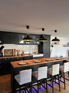 a kitchen with a large island with white chairs at La Fabrique - Relaxing break with Jacuzzi in Crécy-en-Ponthieu