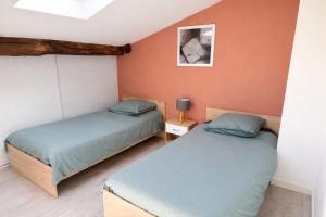 two beds in a room with orange walls at Duplex 2 chambres Meximieux centre ville in Meximieux