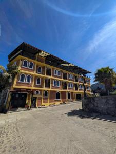 a large yellow building with white windows and palm trees at Hotel Bello Amanecer in Mineral del Chico