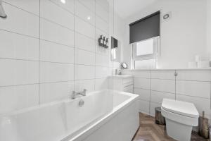 a white bathroom with a tub and a toilet at Lesmahagow Hilltop View in Lesmahagow