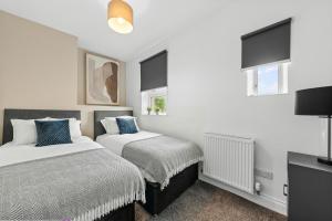 a bedroom with two beds and a flat screen tv at Lesmahagow Hilltop View in Lesmahagow