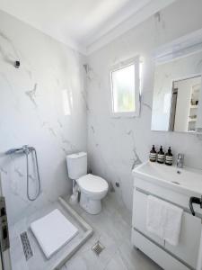 a white bathroom with a toilet and a sink at Hotel BlueBalcony in Golem +22 photos
