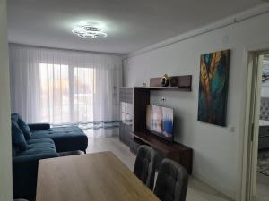 a living room with a table and a couch and a television at Apartment White Tower Residential in Ploieşti
