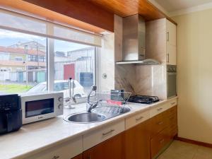 a kitchen with a sink and a microwave and a window at Cozy & Calm Beach House in Ovar +11 photos