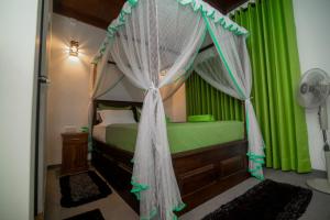 a bedroom with a canopy bed with green curtains at Rainforest Hide View in Deniyaya