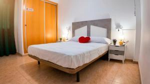a bedroom with a large bed with a red heart pillow at Apartalux San Pedro Playa in San Pedro del Pinatar