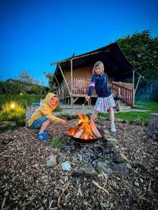 two children playing around a fire in front of a tent at Little North Field Family Safari Tent Glamping near Harrogate in Harrogate