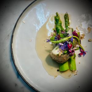 a white plate with a piece of meat and vegetables at La Trouvaille in Waimes