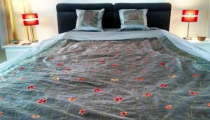 a bed with a blue comforter with red flowers on it at Crystal Palace B&B in Crystal Palace