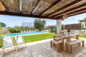 a patio with a table and chairs and a pool at Villa Conguitosby 3VILLAS in Sant Lluis +41 photos