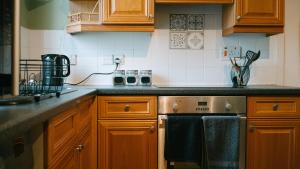 a kitchen with wooden cabinets and a stove top oven at Central Dundee, 1 Bed, Parking, 3 Nights in Dundee