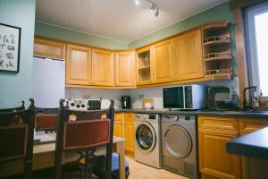 a kitchen with wooden cabinets and a washer and dryer at Central Dundee, 1 Bed, Parking, 3 Nights in Dundee +10 photos