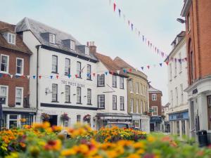una calle de la ciudad con edificios, banderas y flores en The White Horse Hotel, Romsey, Hampshire, en Romsey