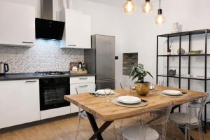 a kitchen with a wooden table and white cabinets at Trilocale spazioso a 6 minuti dal centro in Trieste