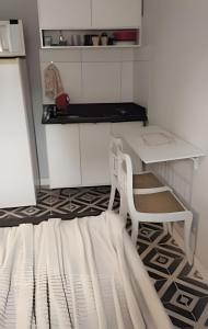 a small kitchen with a white table and a chair at Lotf Privativo in Volta Redonda