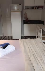 a bedroom with a white bed with a phone on it at Lotf Privativo in Volta Redonda