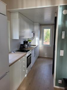 an empty kitchen with white cabinets and a window at Villa Furuviken in Kristinestad