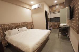 a bedroom with a bed and a desk in it at Hotel Best Inn in Valsād