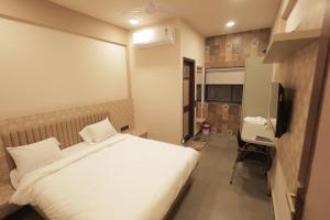 a bedroom with a bed and a desk and a television at Hotel Best Inn in Valsād