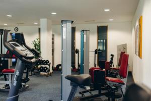 a gym with cardio equipment and red chairs at Hotel Scholz in Aalen
