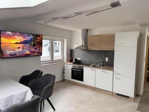 a kitchen with white cabinets and a tv on the wall at Tirol Stay in Ebbs