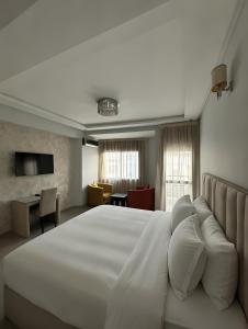 a bedroom with a large white bed and a desk at Appart Hotel Bloom in Al Hoceïma