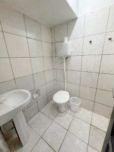 a white bathroom with a toilet and a sink at Quarto no centro 207 in Manaus