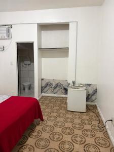 a bedroom with a red bed and a bathroom at Quarto no centro 207 in Manaus