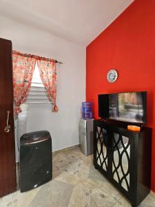 a living room with a tv and a red wall at Caribbean Domicil Apartment 02 in Las Terrenas