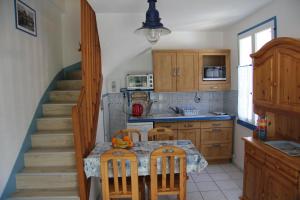 eine Küche mit einem Tisch und Stühlen sowie eine Treppe in der Unterkunft Un petit coin de paradis in Barbâtre